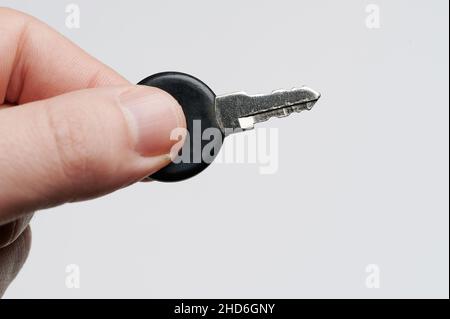 Small key in hand finger isolated on studio background close up view Stock Photo