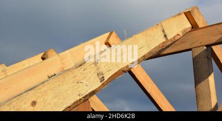 Roofing construction during the roof framing with a close-up of wooden roof truss, rafters and ridge beam. Stock Photo