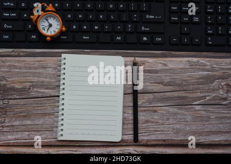 Top view of notepad with alarm clock on a keyboard. Deadline concept Stock Photo