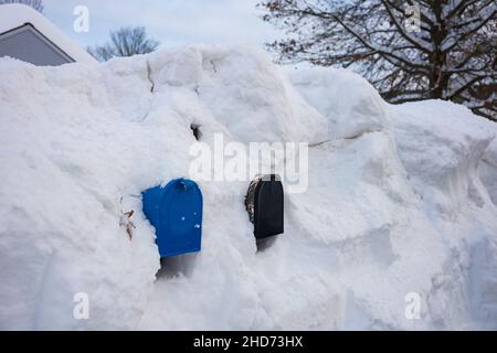 Mailboxes, located along a neighborhood road are covered in snow after a winter blizzard. Stock Photo