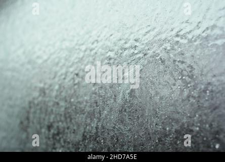 Frozen car window, frozen glass texture. A car window covered with ice in winter. Stock Photo