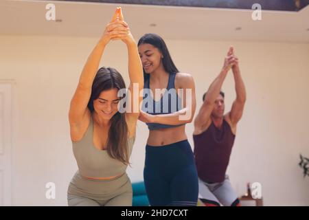 Smiling female instructor assisting young woman in practicing yoga pose during exercise session Stock Photo