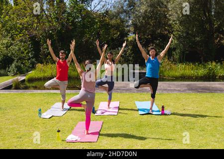 Female instructor teaching yoga to men and woman in park Stock Photo
