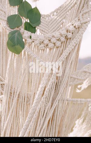 Knitted lace white macrame decorated with green leaves Stock Photo