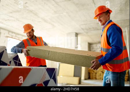 Two builders unload construction material at storehouse Stock Photo