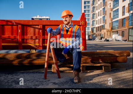 Construction worker rest sitting on pipe pile Stock Photo