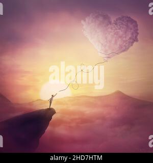 A person on the cliff and a heart shaped cloud like a kite raising up in the air. Magical scene, love and romance concept. Pink sunset clouds, peacefu