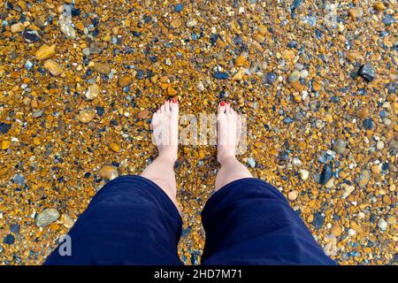 Feet dipping in the sea on a shingle beach in Saltdean, UK Stock Photo
