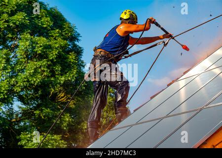 Worker washing photovoltaic panels on roof with pressurized water Stock Photo