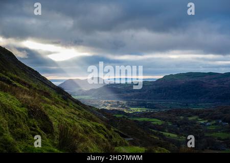 A shaft of sun light shines through a gap in the clouds into the valley seen from Cnicht mountainside. Croesor, Gwynedd, Wales, UK, Britain Stock Photo