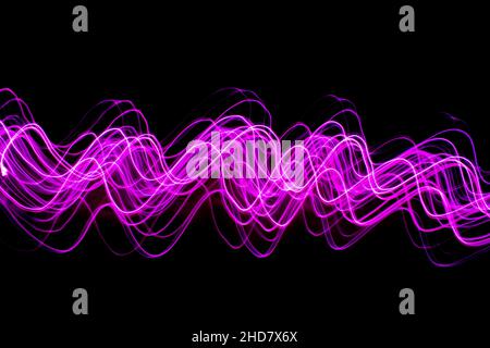 Abstract pink swirl against black background, light painting shiny swirl. Long exposure photography. Stock Photo