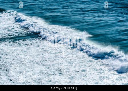safire colored waves of the sea with its surf approaching the beach seen from above Stock Photo