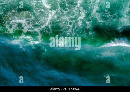 safire colored waves of the sea with its surf approaching the beach seen from above Stock Photo