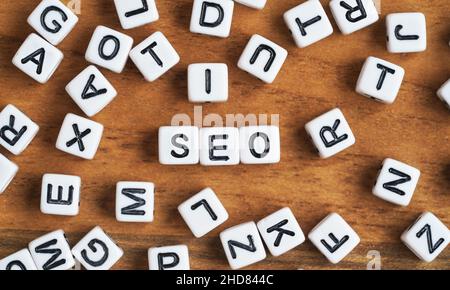 Small white and black bead cubes on wooden board, letters in middle spell SEO - Search Engine Optimization concept Stock Photo