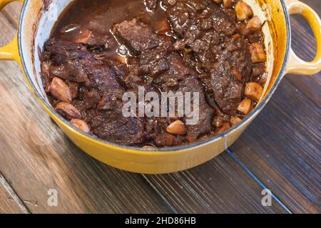 A yellow dutch oven with homemade braised beef short ribs in wine and garlic Stock Photo