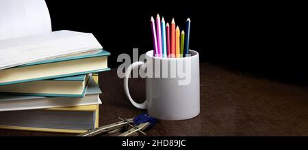 Concept of education and preparation for school. Stack of colorful books, pencils on black background, beginning of school year Stock Photo