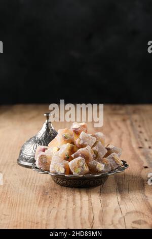 Turkish delight with pistachio in a copper plate on a wooden floor, text space Stock Photo