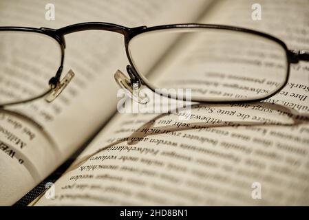 Close up of reading glasses lying on open book, selective focus Stock Photo