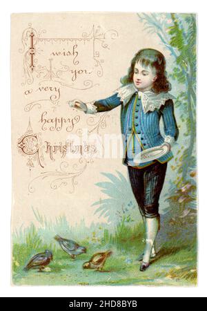 Original Victorian scrapbook Christmas card cutting - boy with long hair in Little Lord Fauntleroy suit, feeding birds, Christmas greetings, late 1890's, UK Stock Photo