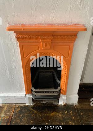 Victorian fire place in a house in Northampton UK old style round hath grate orange designed fireplace shelf shelving small bedroom stylish artwork Stock Photo