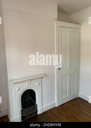 Victorian fire place in a house in Northampton UK door style open painted white arch arched shelf handle grate wood floor flooring oak cupboard design Stock Photo