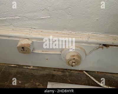 Electrical switches and fuses Northampton UK old plastic design Victorian style wall skirting board white painted electrical electrician le round pins Stock Photo