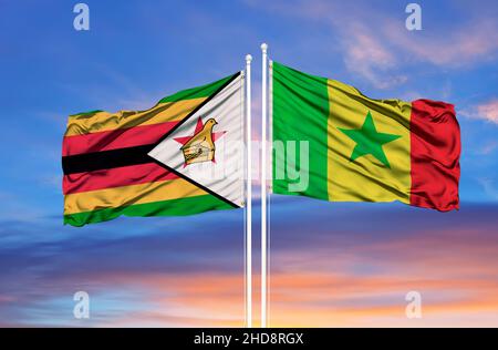 Senegal and Zimbabwe two flags on flagpoles and blue cloudy sky Stock Photo