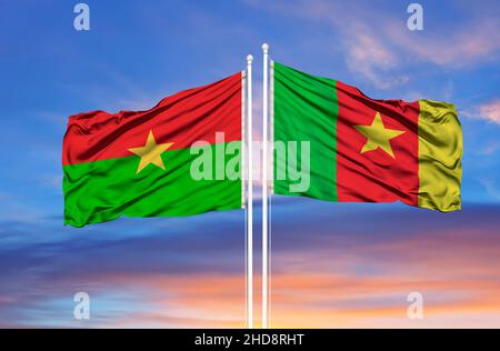 Cameroon and Burkina Faso two flags on flagpoles and blue cloudy sky Stock Photo