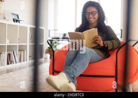Smiling black woman in glasses reading book Stock Photo