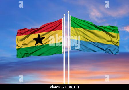 Ghana and Gabon two flags on flagpoles and blue cloudy sky Stock Photo