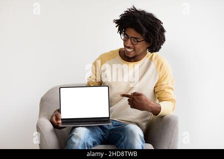 Great Website. Smiling Young Black Man Pointing At Blank Laptop Screen Stock Photo