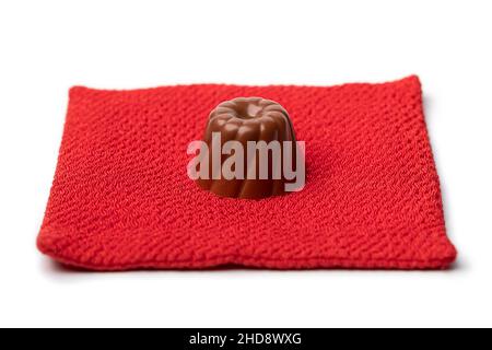 Single chocolate bonbon on a red pillow isolated on white background close up Stock Photo