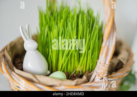 Easter composition. Basket with grass, dyed egg and Easter bunny. Happy Easter  Stock Photo