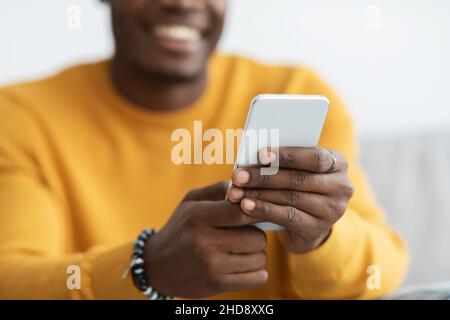 Unrecognizable black guy using mobile phone at home Stock Photo