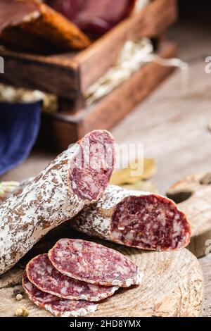 Smoked sliced salami on a old wooden table. Sausages with edible mold Stock Photo