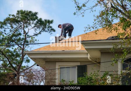 NEW ORLEANS, LA, USA - DECEMBER 31, 2021: Worker demolishing chimney as part of roof renovation on residential rooftop Stock Photo