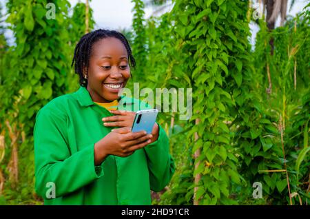 excited beautiful african female farmer using her phone Stock Photo