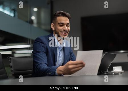Smiling arabic businessman checking reports in modern office Stock Photo