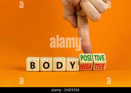 Body positive or negative symbol. Psychologist turns cubes, changes words body negative to body positive. Beautiful orange background, copy space. Psy Stock Photo