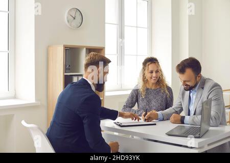 Happy family signs lease or purchase agreement given to them by bank manager or real estate agent. Stock Photo