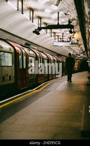 Rear shot of a man standing near the empty train on the subway, Kings Cross, London, Stock Photo