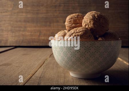 Walnuts in a ceramic bowl on a dark wooden background Stock Photo