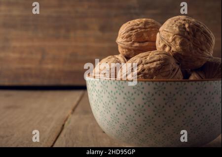 Walnuts in a ceramic bowl on a dark wooden background Stock Photo