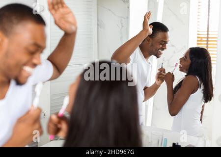 Morning Fun. Happy Black Spouses Singing With Toothbrushes In Bathroom Stock Photo