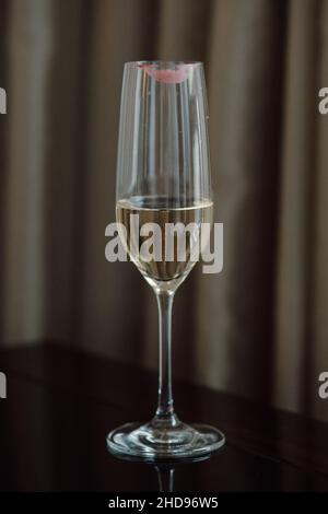 Single Champagne Flute on Dark Background with Pink Lipstick Print on Glass Stock Photo