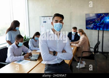 Middle eastern businessman wearing medical mask posing in office during corporate meeting Stock Photo