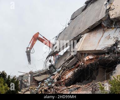 Heavy equipment being used to tear tearing down building construction. Excavator working on a demolition site Stock Photo