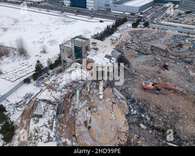 Heavy equipment being used to tear tearing down building construction. Excavator working on a demolition site. Drone view  Stock Photo