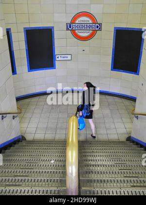 A young Asian woman rushing for the train at Aldgate East tube station on the London underground. Stock Photo