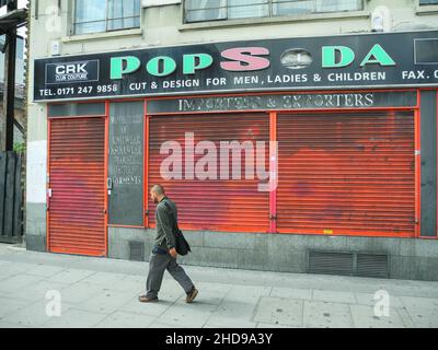 A solitary Asian man walking past Pop Soda, Whitechapel High Street, Aldgate East, London, England, U.K. Stock Photo